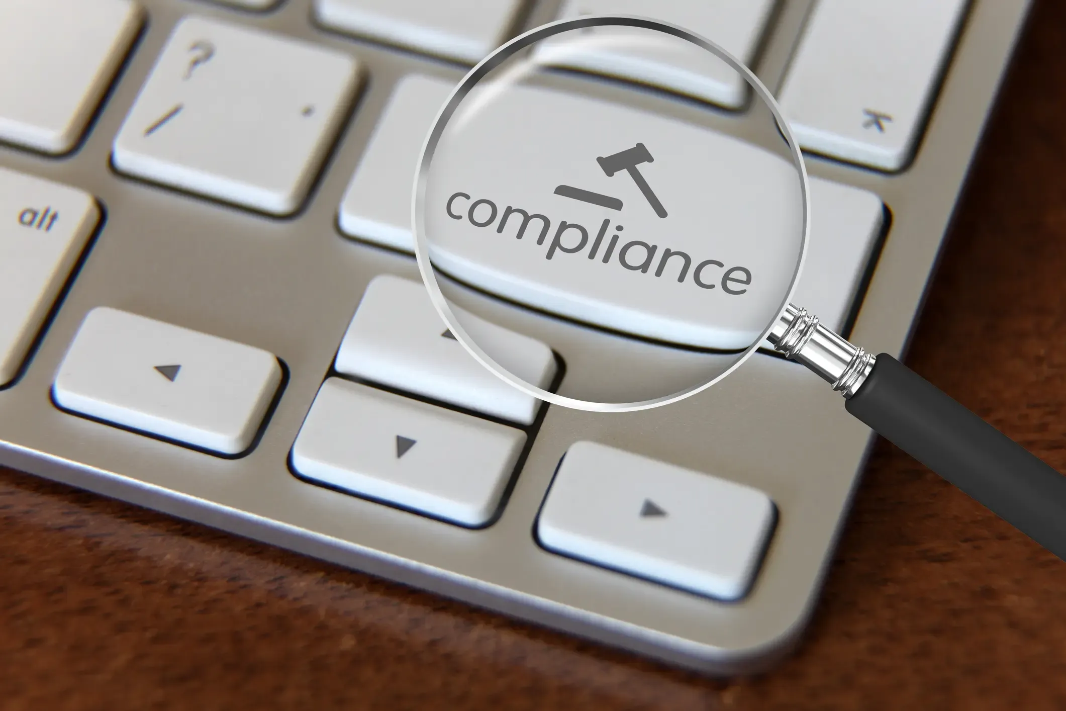 Image shows a keyboard with a button labeled "compliance" under a magnifying glass.